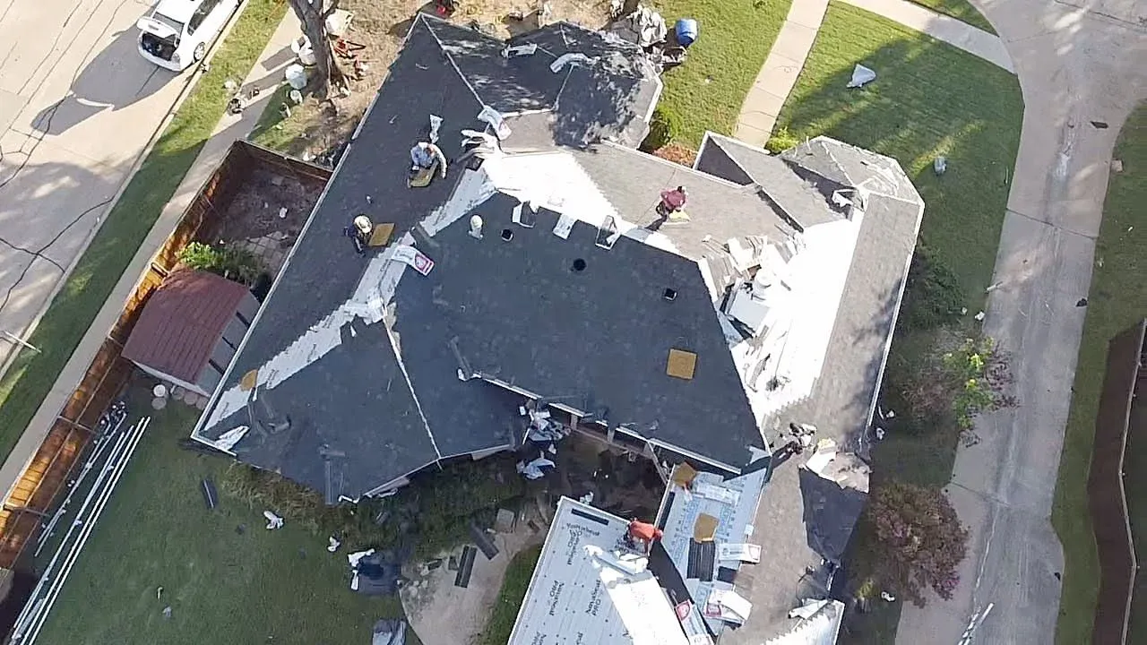 Aerial view of a roof replacement in progress, new shingles going on over underlayment