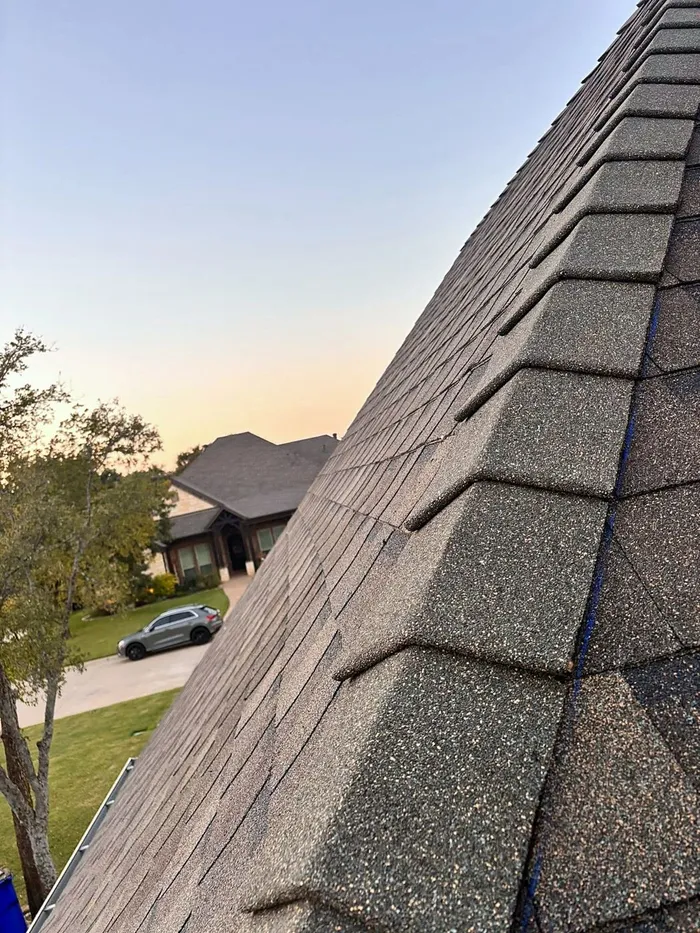 Ridge cap shingles on a finished roof at sunset