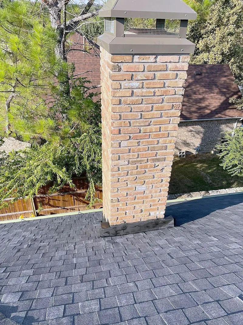 New dark shingles laid up against a brick chimney